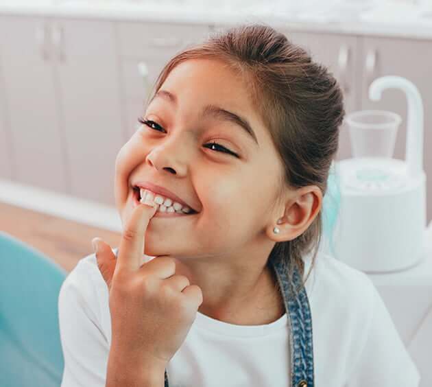 young girl pointing at tooth