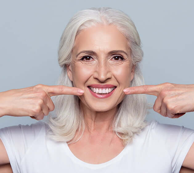 senior woman pointing at teeth