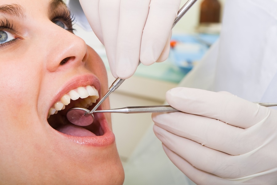 oral cancer screening on female patient in dental chair to see the symptoms of oral cancer